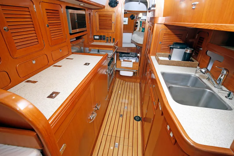 Slide: The Image of Luxurious 2012 Hylas 49CC yacht interior with wooden cabinetry and modern kitchen amenities. - 122