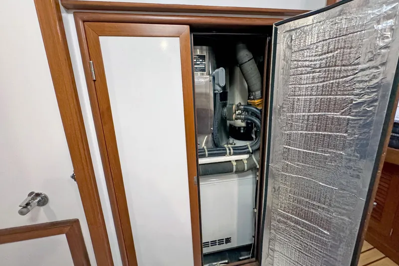 Slide: The Image of Engine compartment of a 2012 Hylas 49CC yacht, featuring insulated door and visible piping. - 139