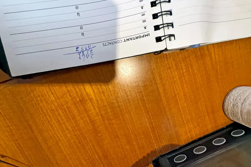 Slide: The Image of Open notebook on wooden table with handwritten contact number, spiral binding visible. - 146