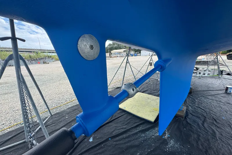 Slide: The Image of Blue hull of a 2012 Hylas 49CC sailboat on stands, showing rudder and propeller shaft. - 187