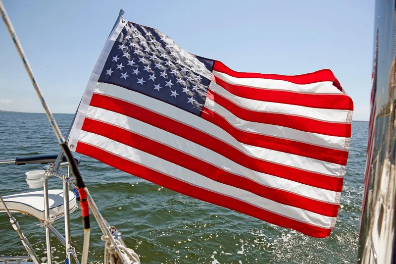 Slide: The Image of American flag waving on a 2012 Hylas 49CC sailboat in open water. - 89