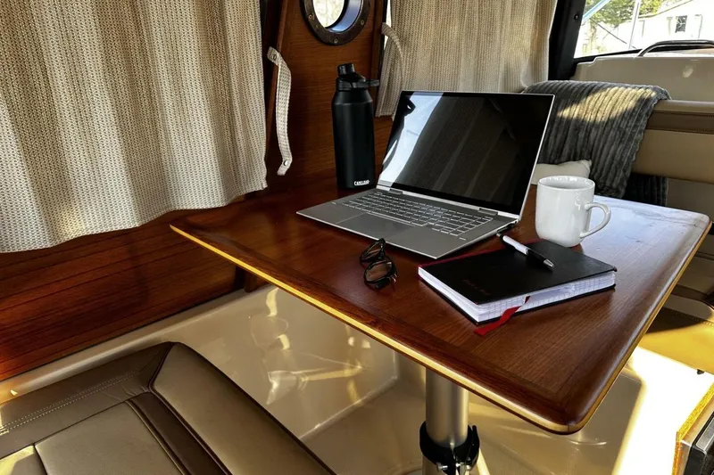 Slide: The Image of Cozy workspace inside 2019 Ranger Tugs R-23 boat with laptop, notebook, and coffee mug. - 10