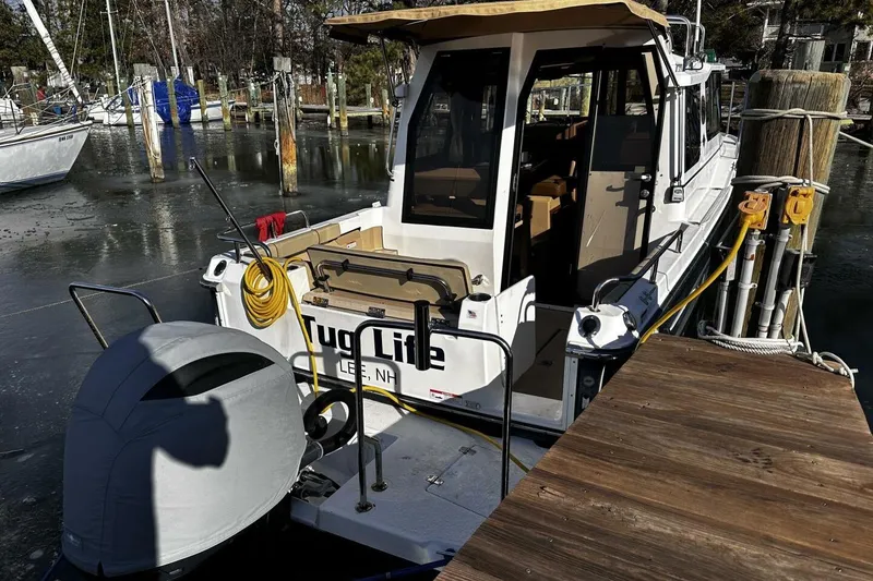 Slide: The Image of 2019 Ranger Tugs R-23 docked, featuring covered outboard motor and spacious deck area. - 27