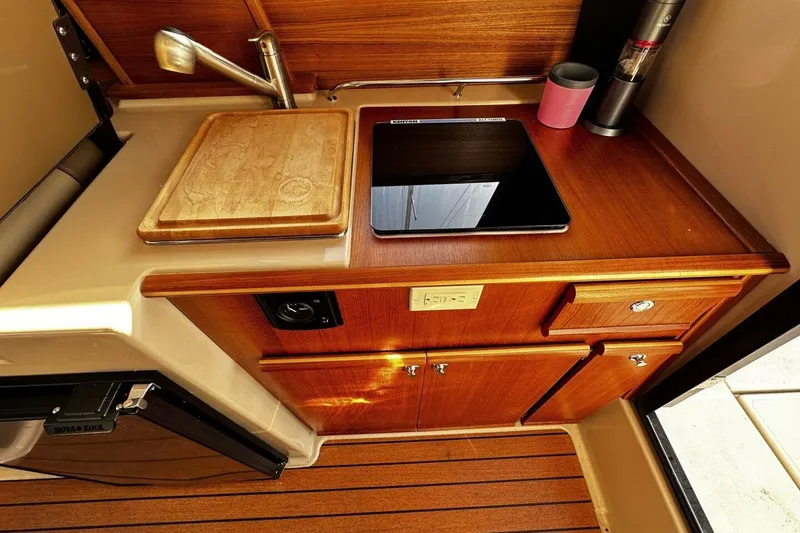 Slide: The Image of 2019 Ranger Tugs R-23 boat kitchen with wooden cabinetry and modern appliances. - 9