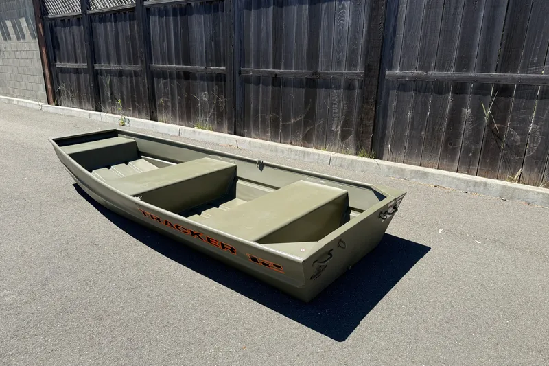 Slide: The Image of 2026 Tracker Grizzly 12 Jon boat on pavement, near wooden fence, in sunlight. - 10