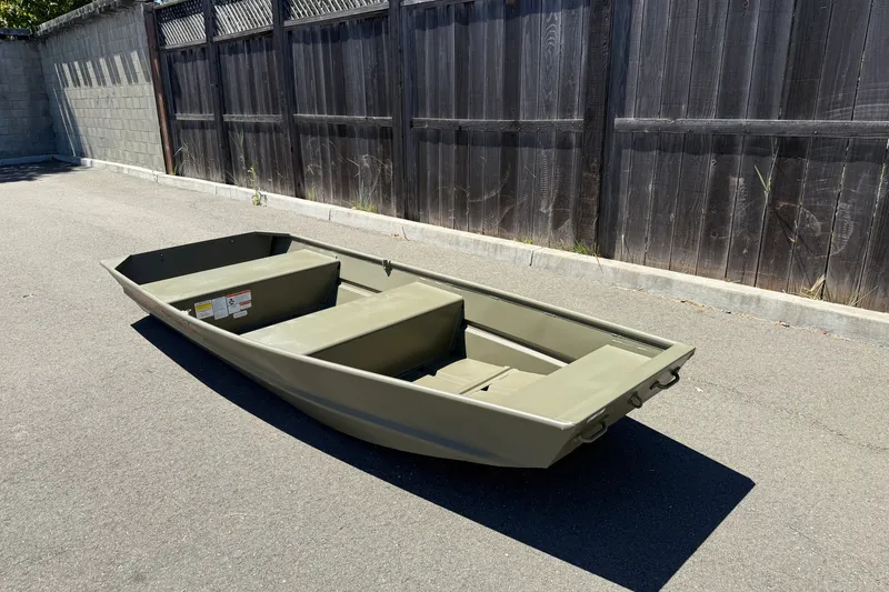 Slide: The Image of 2026 Tracker Grizzly 12 Jon boat on pavement, near wooden fence, in sunlight. - 9