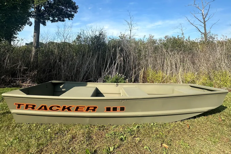 The Image of 2026 Tracker Grizzly 10 Jon boat on grassy field, surrounded by trees and shrubs. - 0