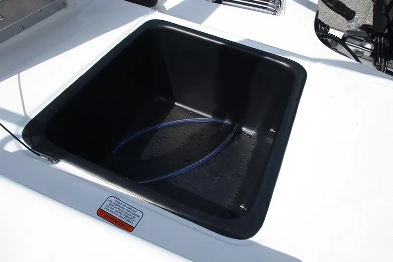 Slide: The Image of Livewell compartment on 2026 Tahoe T18 boat, featuring a black interior and drainage hose. - 25