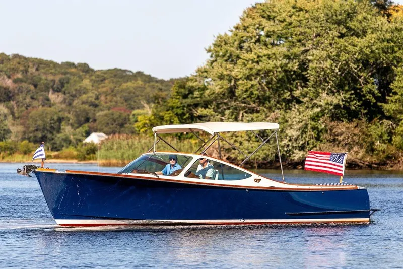 The Image of 2003 Hinckley T29R boat cruising on a scenic lake with American flag. - 0