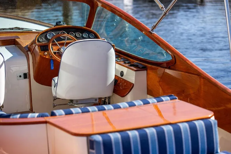 Slide: The Image of Interior of a 2003 Hinckley T29R boat with wooden dashboard and striped seating. - 12