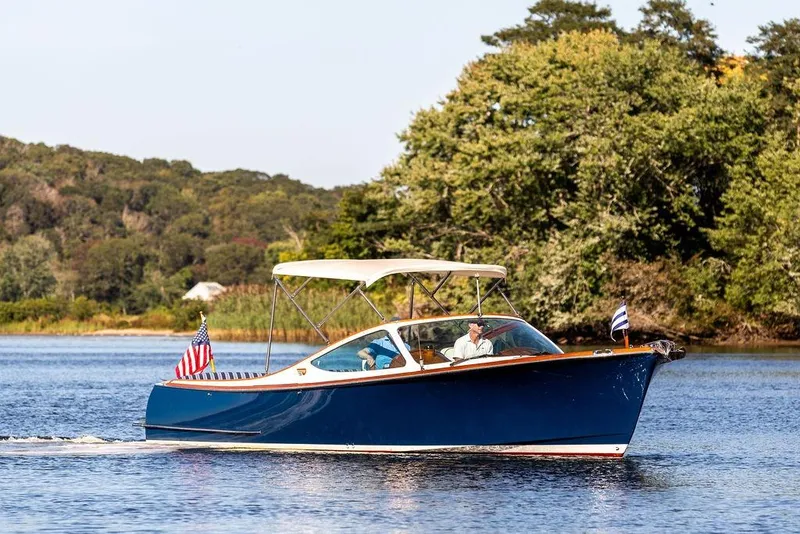 Slide: The Image of 2003 Hinckley T29R boat cruising on a serene lake with lush green trees. - 2