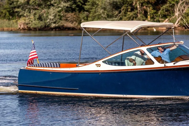 Slide: The Image of 2003 Hinckley T29R boat cruising on a lake with an American flag. - 5