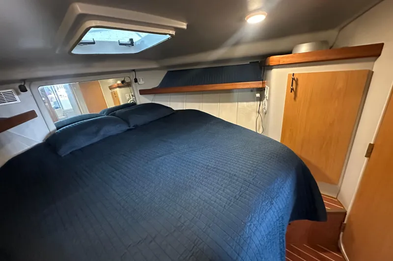 Slide: The Image of 1996 Mainship 40 Sedan Bridge cabin with bed, wooden cabinets, and overhead hatch. - 38