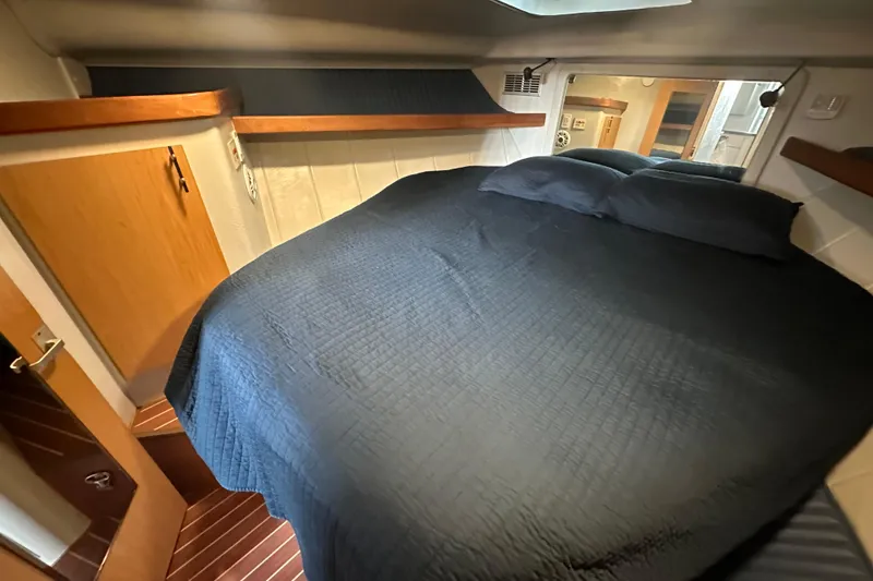 Slide: The Image of 1996 Mainship 40 Sedan Bridge cabin interior with blue bedding and wooden cabinetry. - 40