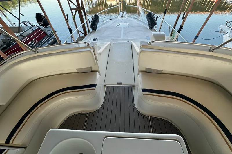 Slide: The Image of 1996 Mainship 40 Sedan Bridge interior with white seating and docked pontoon boat. - 5