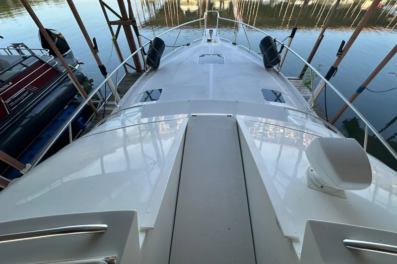Slide: The Image of 1996 Mainship 40 Sedan Bridge boat deck with seating, docked by the water. - 6