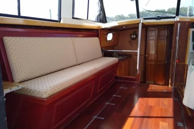Slide: The Image of 1979 Mainship 34 Custom Sedan interior with wooden flooring and cushioned seating. - 11