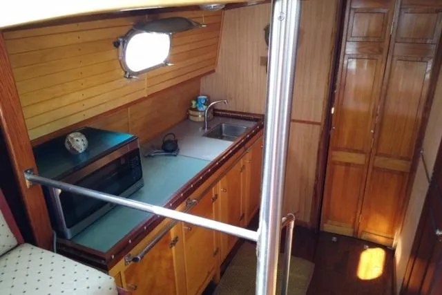 Slide: The Image of 1979 Mainship 34 Custom Sedan interior with kitchenette, featuring wood cabinets and a microwave. - 15