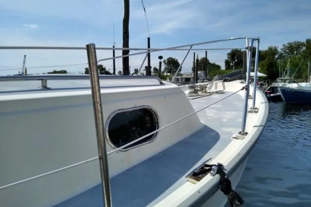 Slide: The Image of 1979 Mainship 34 Custom Sedan boat docked, showcasing deck and railing under clear sky. - 2