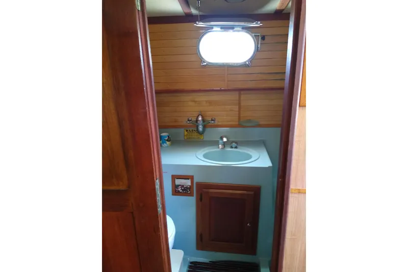 Slide: The Image of 1979 Mainship 34 Custom Sedan bathroom with wooden paneling and compact sink. - 23