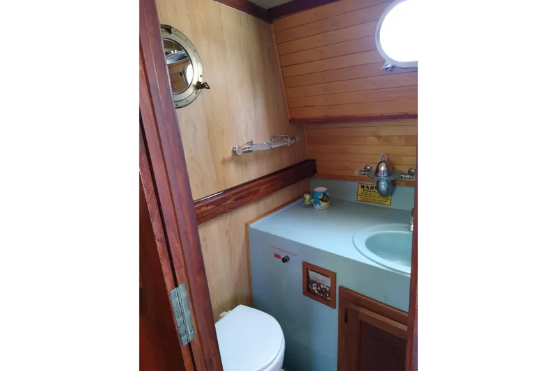 Slide: The Image of 1979 Mainship 34 Custom Sedan bathroom with wooden paneling and porthole window. - 24