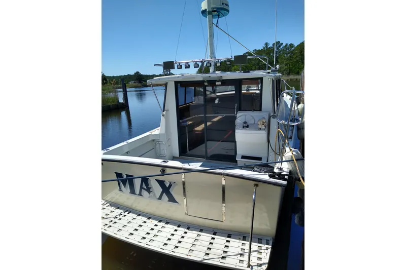 Slide: The Image of 1979 Mainship 34 Custom Sedan docked by a serene riverside. - 3