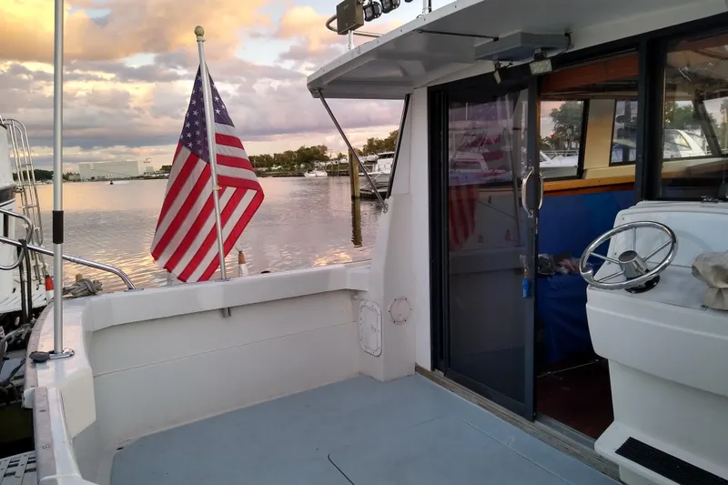 Slide: The Image of 1979 Mainship 34 Custom Sedan with American flag, docked at sunset. - 7