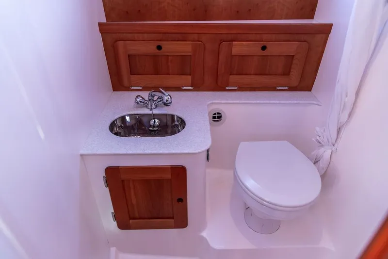 Slide: The Image of 2012 Hunt Yachts Harrier 36 Express bathroom with sink, toilet, and wooden cabinetry. - 23
