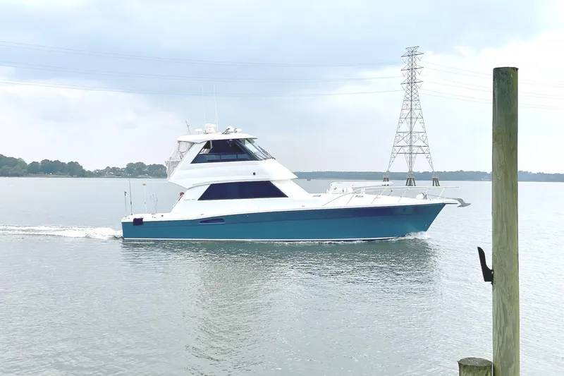 The Image of 1999 Riviera Convertible SF yacht cruising on calm waters under a cloudy sky. - 1