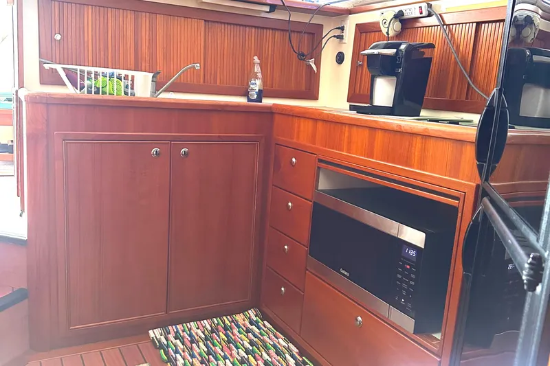 Slide: The Image of 1999 Riviera Convertible SF yacht kitchen with wooden cabinets, microwave, and coffee maker. - 25