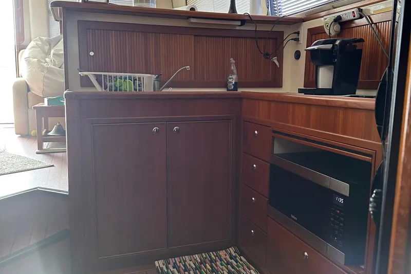 Slide: The Image of 1999 Riviera Convertible SF yacht kitchen with wooden cabinets, microwave, and coffee maker. - 27