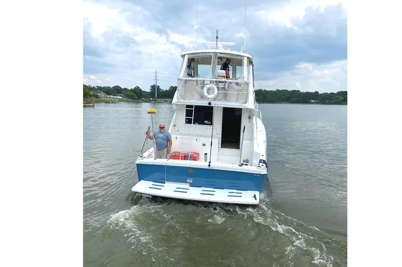 Slide: The Image of 1999 Riviera Convertible SF boat on calm water, with two people on deck. - 3