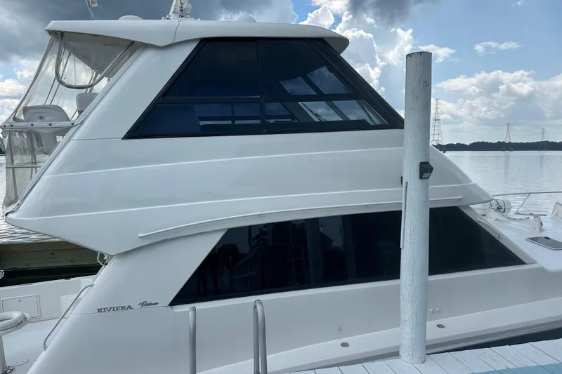 Slide: The Image of 1999 Riviera Convertible SF yacht docked by a serene lake under a cloudy sky. - 30