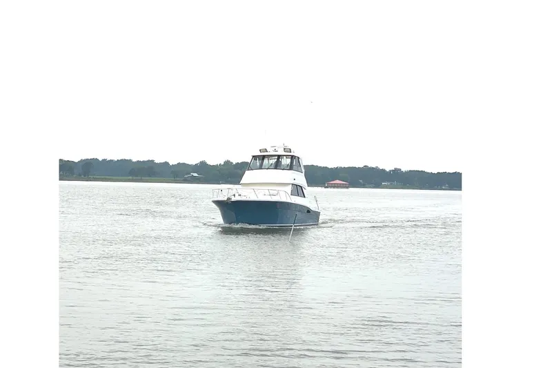 Slide: The Image of 1999 Riviera Convertible SF boat cruising on a calm lake with distant shoreline. - 8