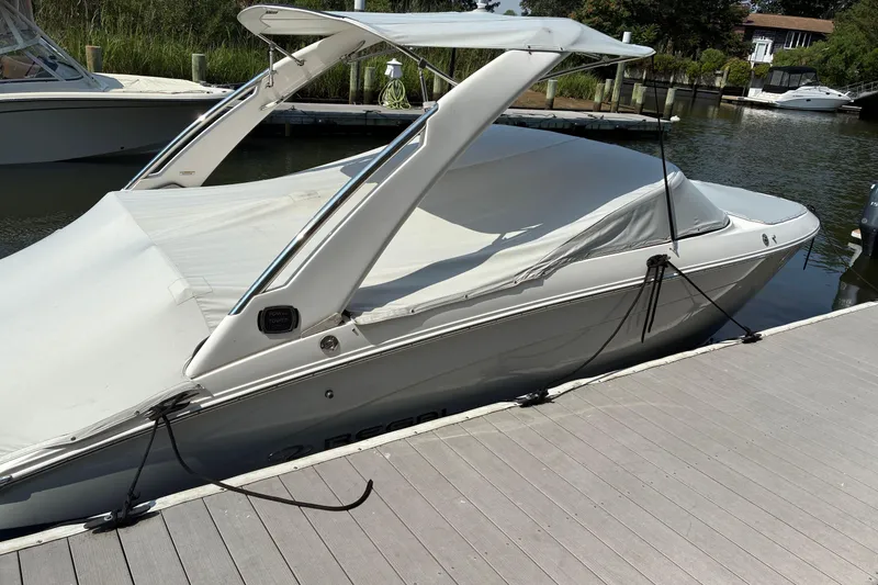 Slide: The Image of 2020 Regal LS4 boat docked with cover, sleek design, calm water background. - 5