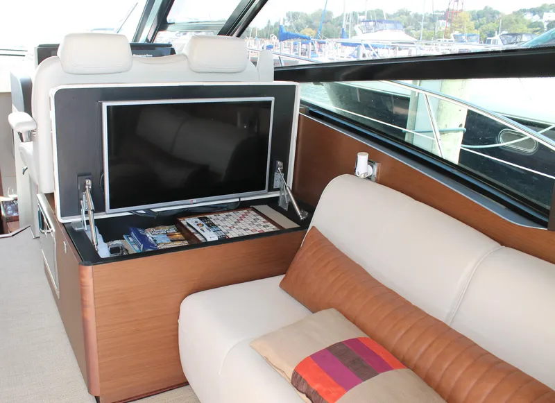 Slide: The Image of 2015 Sea Ray 470 Sundancer interior with TV, sofa, and window view. - 11