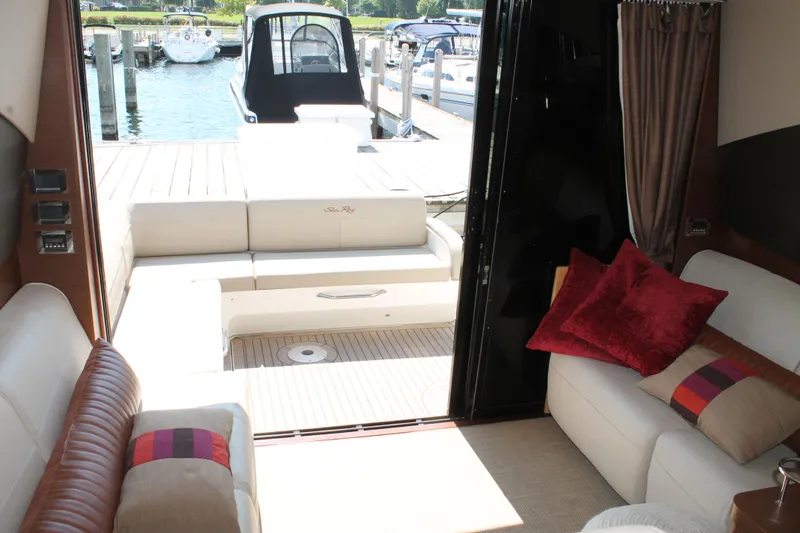 Slide: The Image of 2015 Sea Ray 470 Sundancer interior with plush seating and marina view. - 12