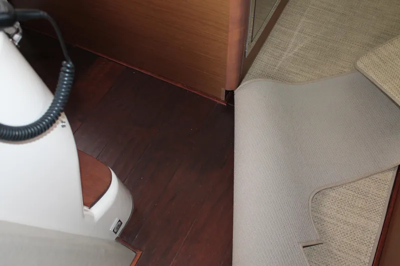 Slide: The Image of Interior of 2015 Sea Ray 470 Sundancer with wooden flooring and partially lifted carpet. - 122