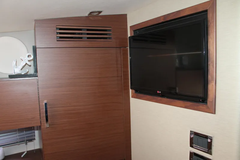 Slide: The Image of Interior of 2015 Sea Ray 470 Sundancer with wall-mounted TV and wooden paneling. - 38
