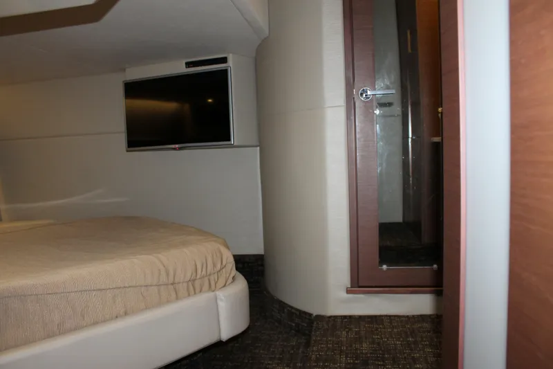 Slide: The Image of Interior cabin of 2015 Sea Ray 470 Sundancer with bed, TV, and bathroom door. - 97