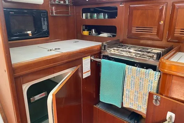 Slide: The Image of 2003 Beneteau Oceanis Clipper 361 yacht kitchen with stove, microwave, and wooden cabinetry. - 22
