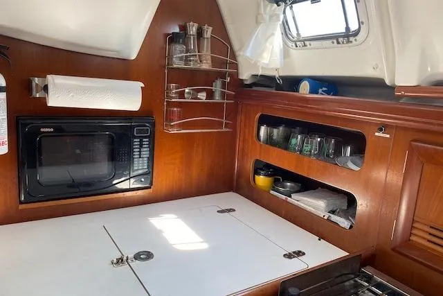 Slide: The Image of Galley of 2003 Beneteau Oceanis Clipper 361 with microwave, storage, and wooden cabinetry. - 23