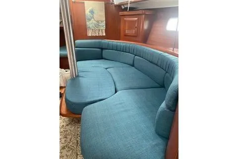 Slide: The Image of 2003 Beneteau Oceanis Clipper 361 interior with blue cushioned seating and wooden accents. - 28