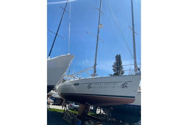 Slide: The Image of 2003 Beneteau Oceanis Clipper 361 sailboat on land, named "Sweet Dreams," under clear blue sky. - 38