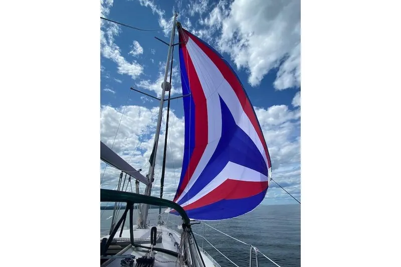Slide: The Image of Beneteau Oceanis Clipper 361 sailboat with colorful spinnaker against a cloudy sky. - 5