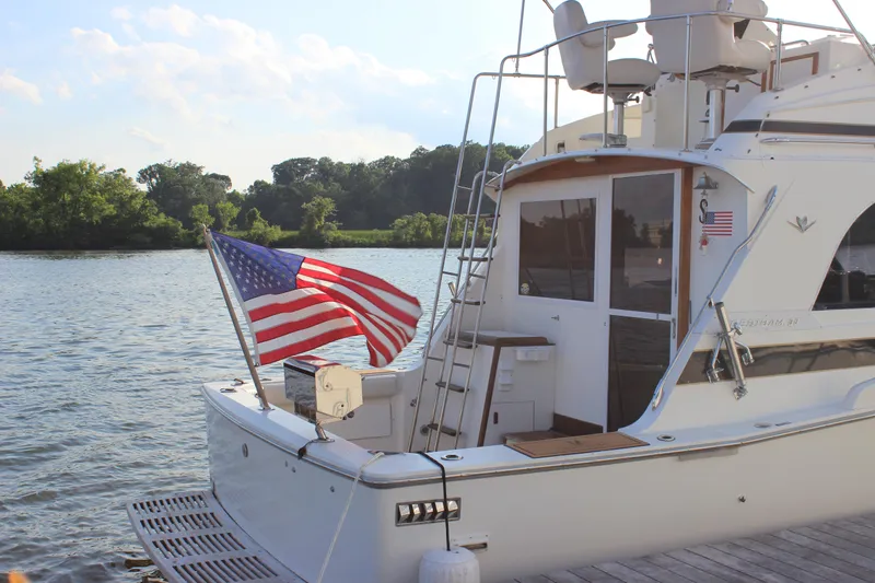 Slide: The Image of 1988 Bertram 33II Flybridge Cruiser docked with American flag. - 13
