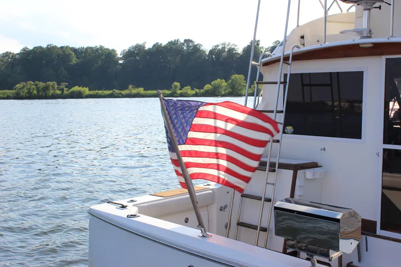 Slide: The Image of 1988 Bertram 33II Flybridge Cruiser with American flag on a serene lake. - 15