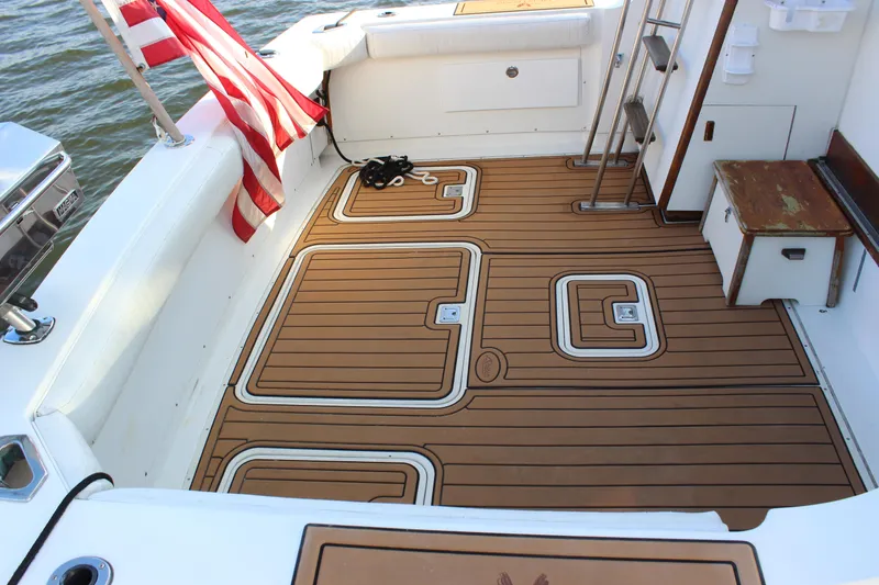 Slide: The Image of 1988 Bertram 33II Flybridge Cruiser deck with teak flooring and American flag. - 20