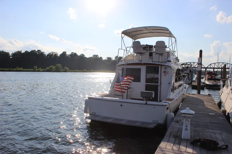 Slide: The Image of 1988 Bertram 33II Flybridge Cruiser docked at a marina with an American flag. - 8