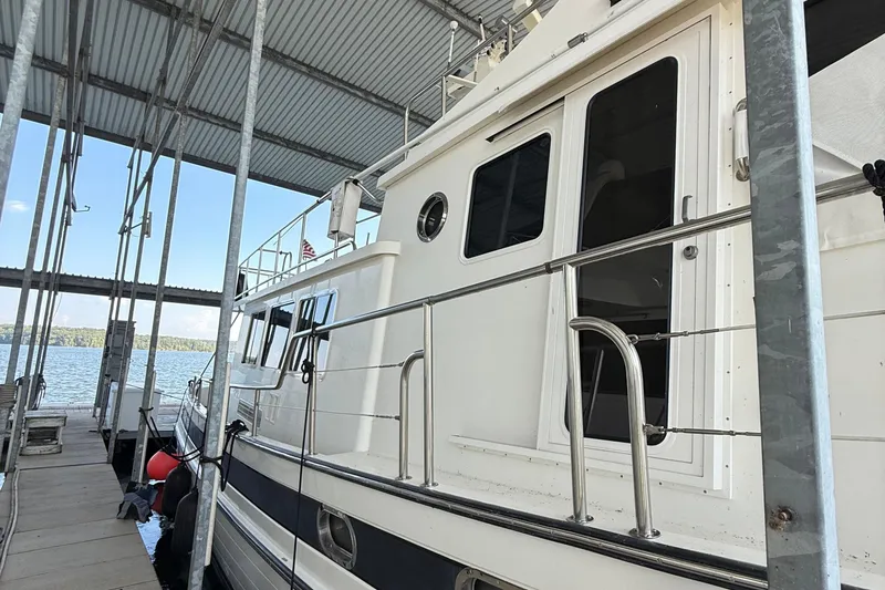 Slide: The Image of 2007 Nordic Tug 54 cruising on a serene lake under a clear blue sky. - 11